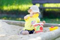 Cute toddler girl playing in sand on outdoor playground. Beautiful baby having fun on sunny warm summer sunny day. Happy Royalty Free Stock Photo