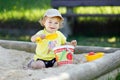 Cute toddler girl playing in sand on outdoor playground. Beautiful baby having fun on sunny warm summer sunny day. Happy Royalty Free Stock Photo