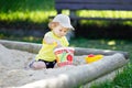 Cute toddler girl playing in sand on outdoor playground. Beautiful baby having fun on sunny warm summer sunny day. Happy Royalty Free Stock Photo