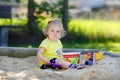 Cute toddler girl playing in sand on outdoor playground. Beautiful baby having fun on sunny warm summer sunny day. Happy Royalty Free Stock Photo