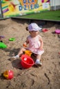 Cute toddler girl playing in sand on outdoor playground. Beautiful baby in red trousers having fun on sunny warm summer day. Child Royalty Free Stock Photo