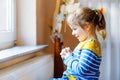 Cute toddler girl praying to God at home. Child using hands for pray and thank Jesus. Christian tradition.