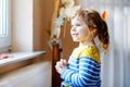 Cute toddler girl praying to God at home. Child using hands for pray and thank Jesus. Christian tradition.