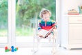 Cute toddler girl reading a book in rocking chair Royalty Free Stock Photo