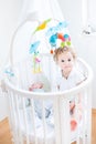 Cute toddler girl sitting in crib of newborn brother Royalty Free Stock Photo