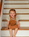 Cute toddler girl sitting on wooden stairs at home Royalty Free Stock Photo