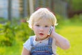 Cute toddler girl talking with mobile phone outdoors Royalty Free Stock Photo