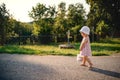 A cute toddler girl walking outdoors on road in countryside in summer. Royalty Free Stock Photo