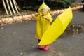 Cute toddler girl wearing yellow stylish raincoat pink rubber boots standing with umbrella Royalty Free Stock Photo