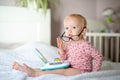 Cute toddler in glasses sitting on bed with a toy laptop. Royalty Free Stock Photo