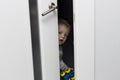 Cute toddler looking out from behind the ajar door