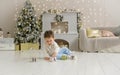 Cute toddler playing with his Christmas present in the decorated room. wooden toy. Family Xmas morning in decorated