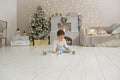 Cute toddler playing with his Christmas present in the decorated room. wooden toy. Family Xmas morning in decorated