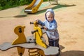 Cute toddler playing on the playground in spring sunny day. funny boy sitting on a swing . Royalty Free Stock Photo