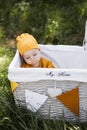 Cute toddler sitting inside decorated wicker basket outdoors