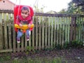 Cute toddler swinging in her backyard in front of old fence Royalty Free Stock Photo