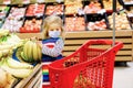 Cute todler girl with medical mask pushing shopping cart in supermarket. Little child buying fruits. Kid grocery