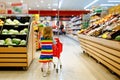 Cute todler girl pushing shopping cart in supermarket. Little child buying fruits. Kid grocery shopping. Adorable baby Royalty Free Stock Photo