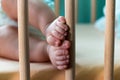 Cute toes and feet of the newborn baby touching crib pillar