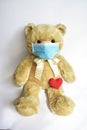 Cute toy bear in the blue mask with red heart. Teddy bear wearing face mask protective for spreading of disease virus CoV-2 Corona