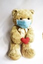 Cute toy bear in the blue mask with red heart. Teddy bear wearing face mask protective for spreading of disease virus CoV-2 Corona