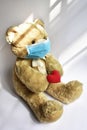 Cute toy bear in the blue mask with red heart. Teddy bear wearing face mask protective for spreading of disease virus CoV-2 Corona