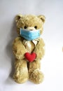 Cute toy bear in the blue mask with red heart. Teddy bear wearing face mask protective for spreading of disease virus CoV-2 Corona