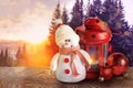 Cute toy snowman, lantern and Christmas balls on wooden table in winter forest. Space for text Royalty Free Stock Photo