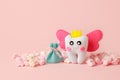 Cute toy for Tooth Fairy Day as funny smiling cartoon character of tooth fairy with crown, wings on pink background, copy space