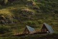 Cute triangle houses on a background of green grass of high mountains