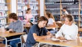 Cute tween girl and intelligent boy studying together in library, reading books Royalty Free Stock Photo