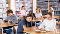 Cute tween girl and intelligent boy studying together in library, reading books Royalty Free Stock Photo