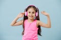 Cute tween girl in pink shirt and wireless headphones over blue background Royalty Free Stock Photo