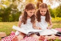 Cute twin girls reading books on green meadow Royalty Free Stock Photo