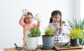 Cute two Asian little girls smiling looking at dirty hands in gloves and apron while having fun planting tree and change flowers