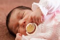 Cute two weeks old newborn baby girl with a pacifier