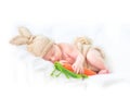 Cute two weeks old smiling newborn baby boy wearing knitted bunny costume and funny carrot toy Royalty Free Stock Photo