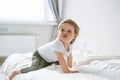 Cute upset baby girl angry child in home clothes sitting on bed at home Royalty Free Stock Photo