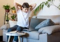 Cute upset boy in white t shirt sitting on the couch in the living room next to laptop and study. Stressed, tired kid Royalty Free Stock Photo