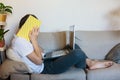 Cute upset boy in white t shirt sitting on the couch in the living room next to laptop and study. Stressed, tired kid. Royalty Free Stock Photo