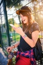 Cute urban girl in skatepark with skateboard using smart phone