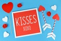 Cute Valentine`s Day composition with picture frame with text `KISSES XOXO`, cupid love arrows and hearts