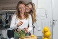 Cute vegan lesbian couple, preparing spinach smoothie. LGTB concept, vegan people