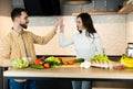 Cute vegetarian couple is hiving five each other while cooking together and looks so happy and healthy. Happy vegan Royalty Free Stock Photo