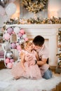 Cute view of beautiful little girl with her father against background of New Year`s decorations