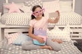 Cute vlogger streaming video. Girl child sit on bed in her bedroom and taking selfie or streaming video. Kid prepare to Royalty Free Stock Photo