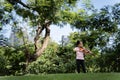 A cute white Asian girl is playing the violin on a grassy hill amid beautiful nature, greenery and sunlight Royalty Free Stock Photo