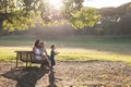 Cute white family spending time in the park - a little boy blowing soap bubbles while his parents sitting on a bench Royalty Free Stock Photo