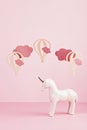 Cute white unicorn over the pink pastel background with clouds and ballons