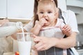 Little girl is sitting in sling and with mother in the kitchen Royalty Free Stock Photo